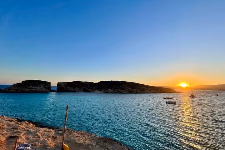 Sunset over Comino Blue Lagoon with boats anchored, scenic Malta to Gozo and Comino half-day cruise view