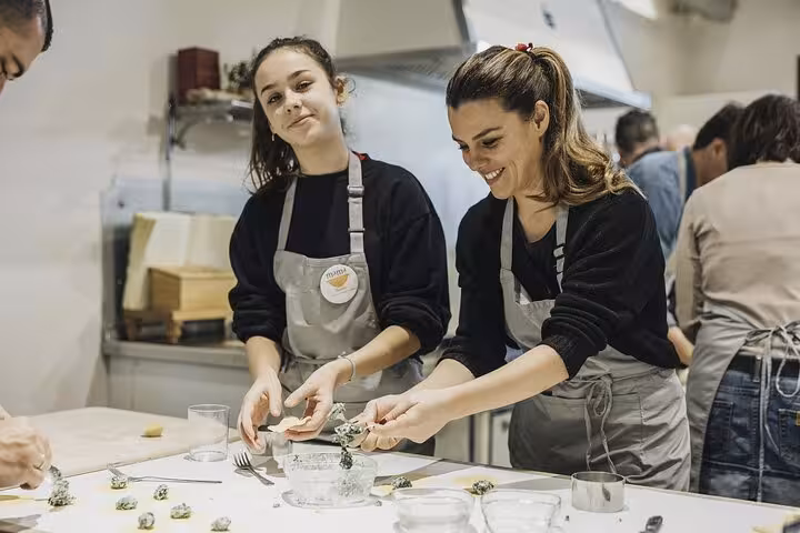 Two women smiling while preparing pasta during MaMa Florence's interactive Corzetti cooking class.