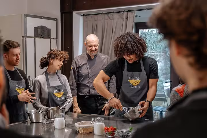 Participants in Mama Florence aprons engage in hands-on learning during a gluten-free Italian cooking class.