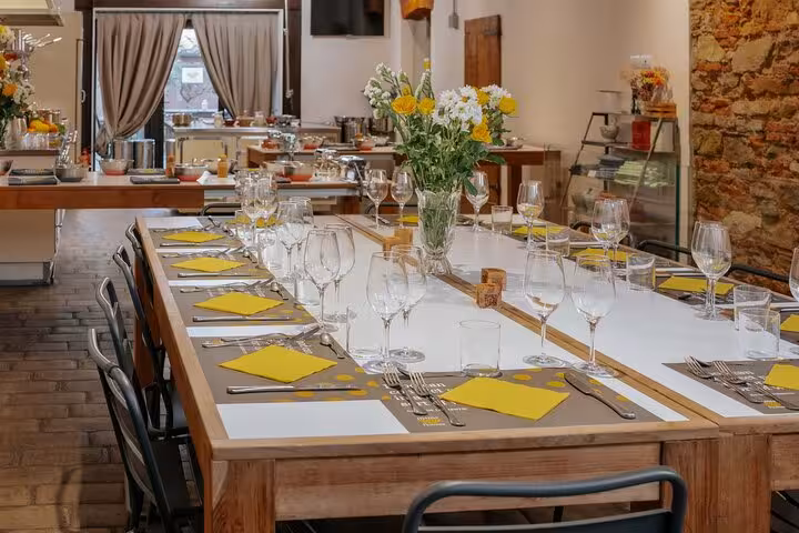 Elegant dining setup at MaMa Florence cooking class with floral centerpiece and wine glasses on wooden tables.