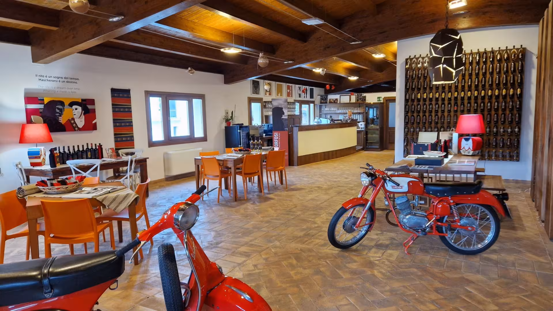 Discover Mamoiada's vibrant tasting room, featuring vintage motorcycles and a welcoming atmosphere for visitors.