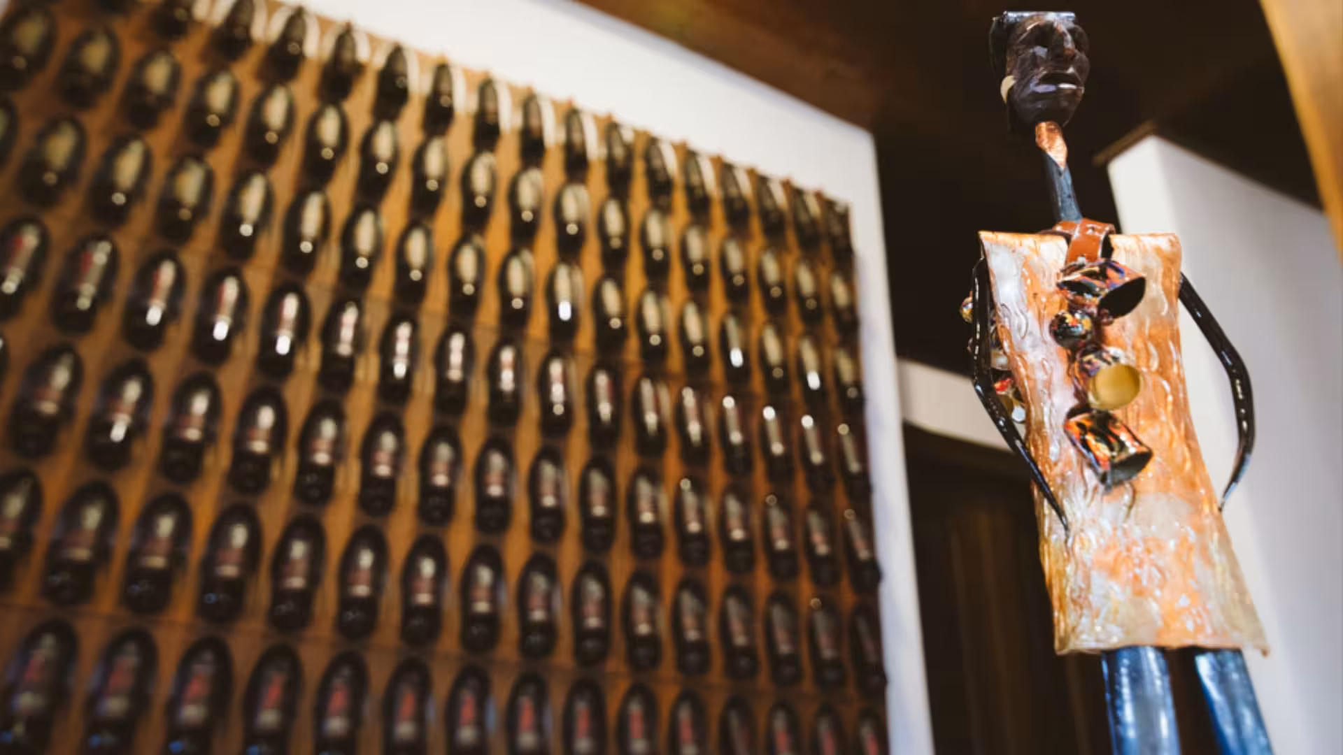 Artistic wine bottle display and sculpture in Mamoiada winery, highlighting Sardinian culture.