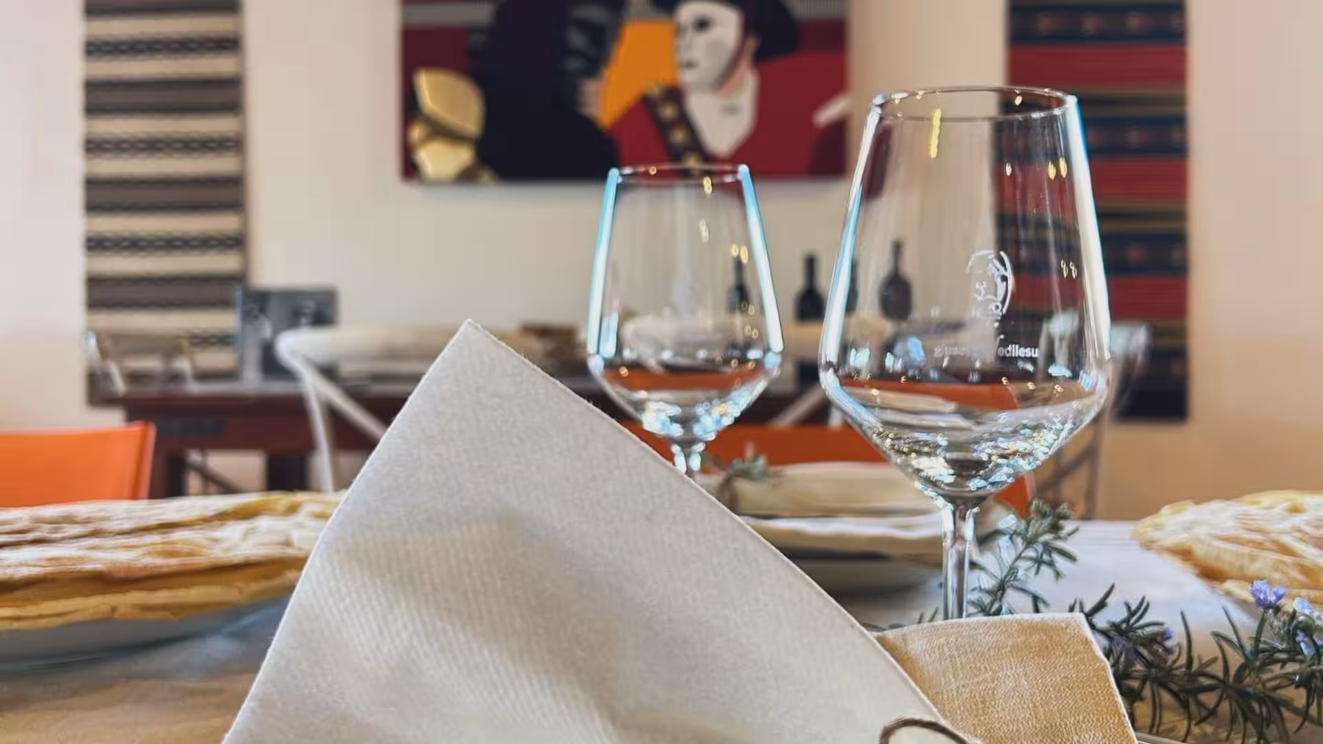 Elegant table setting with wine glasses and traditional decor at Mamoiada winery experience.