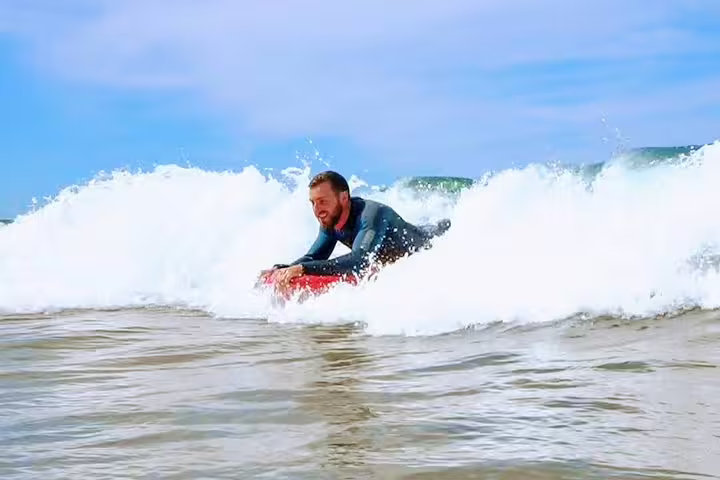 Man riding a wave on a bodyboard at a Lisbon beach, showcasing the excitement of a Lisbon Bodyboard Adventure experience.