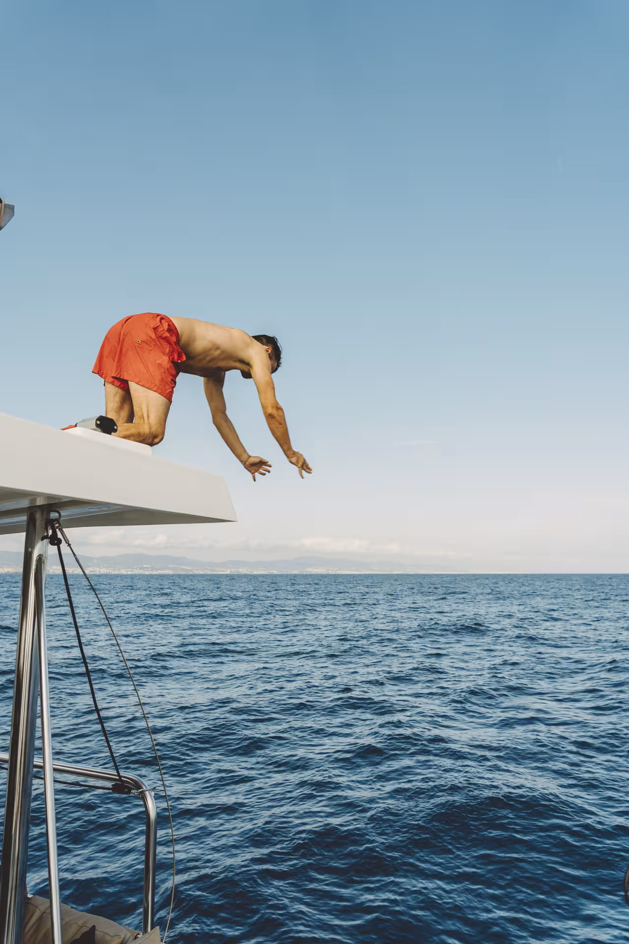 Man diving from Bali 4.1 catamaran on a 2-hour private luxury Barcelona sailing tour in the Med