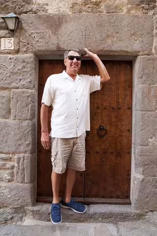 Man in casual attire stands at rustic wooden door in a medieval Catalonian village during a private full-day tour.