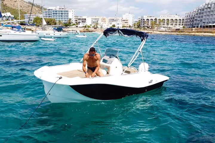 Man enjoying a sunny day on a motorboat in Ibiza's turquoise waters, ideal for exploring without a license.