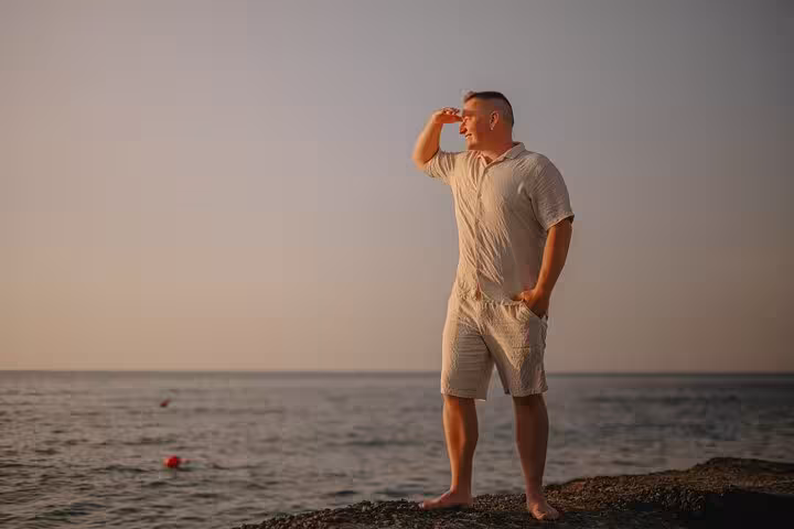 Man admiring the ocean view on a Gouves beach during sunset, perfect for a private photoshoot with scenic backgrounds.