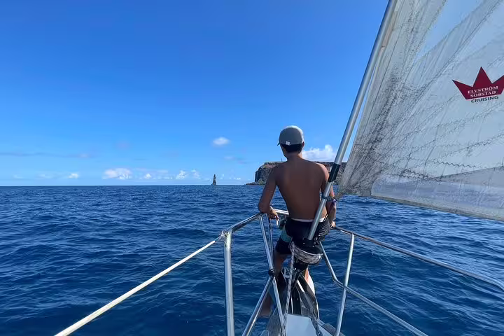 Man enjoying a full day private sailing cruise on a yacht, with clear blue skies and ocean, perfect for a relaxing getaway.