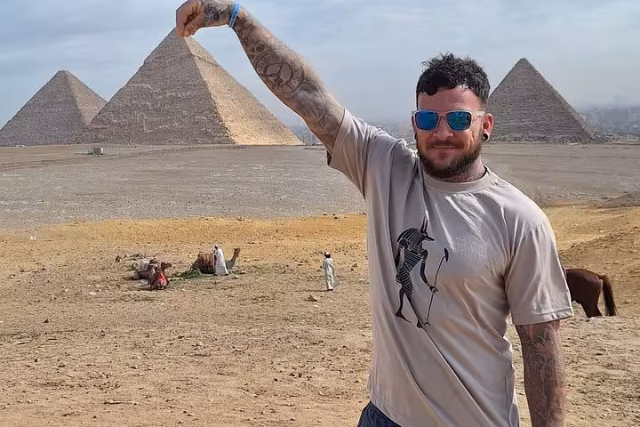 Man playfully posing with the iconic Pyramids of Giza in the background on a private Egyptian tour adventure.
