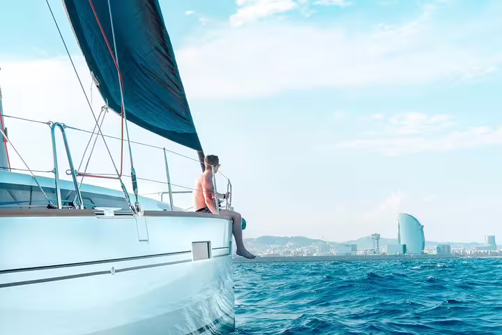 Man relaxing on a sailboat with a city skyline in the background, enjoying a two-hour sailing trip with snacks and drinks.