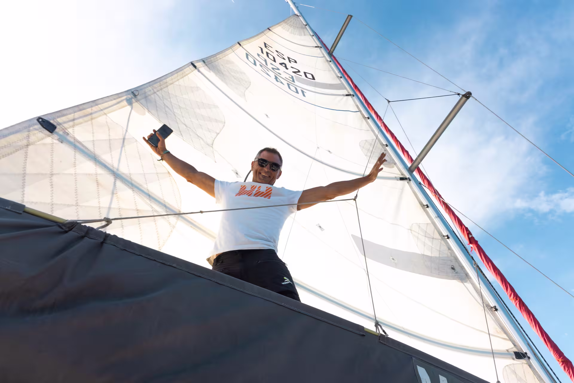 Man joyfully sailing under clear skies in Barcelona during a private 4-hour boat trip experience, embracing the adventure.