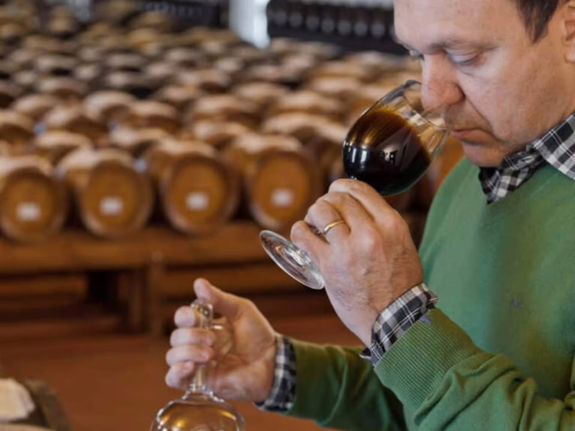 Man smelling aged balsamic vinegar in glass amid wooden barrels on Modena balsamic tasting and tour