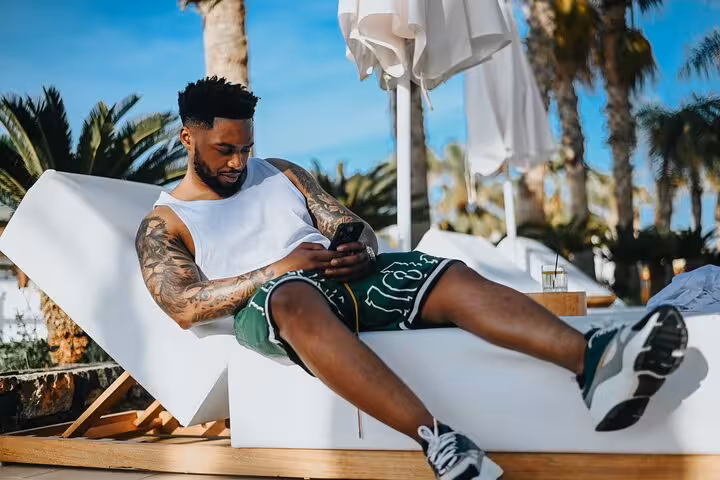 Man relaxing on a sunbed with palm trees in the background during a private photoshoot in Malia, Crete.