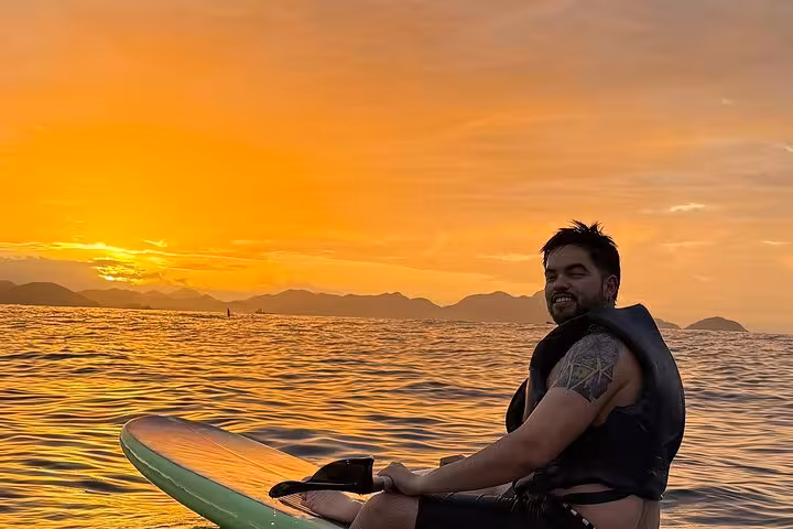 Man enjoying stand-up paddleboarding at sunrise in Copacabana, highlighting a unique river adventure.