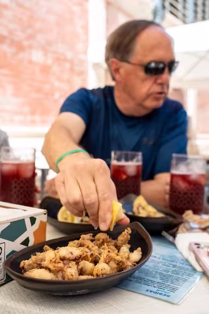 Man enjoying traditional tapas with sangria on a sunny day in Seville's historic district.