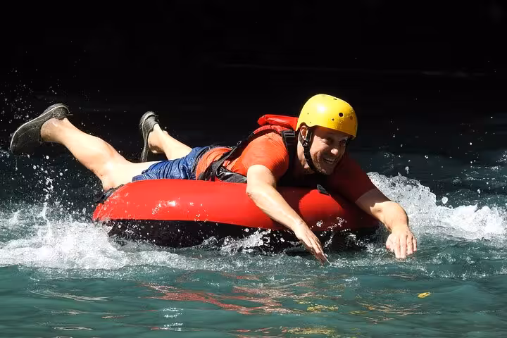 Man smiling while tubing down the vibrant waters of Rio Celeste on an adventure tour.