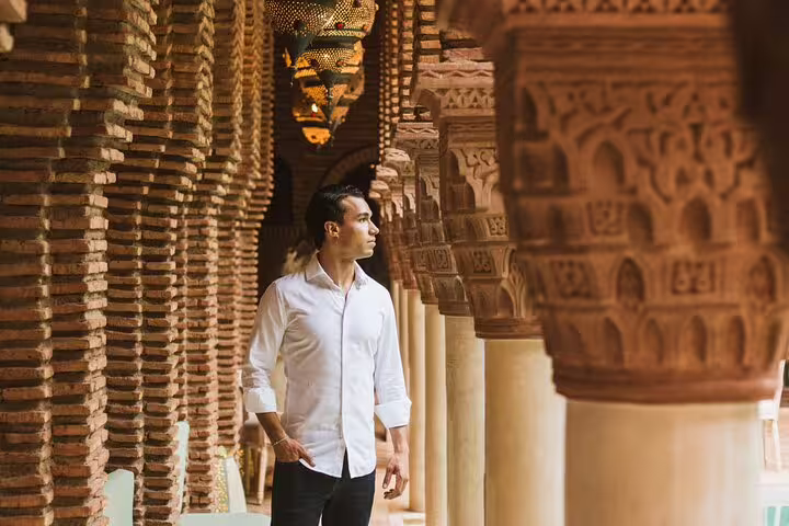 Man in a white shirt exploring the ornate architectural columns in Marrakesh, ideal for cultural photo shoots.