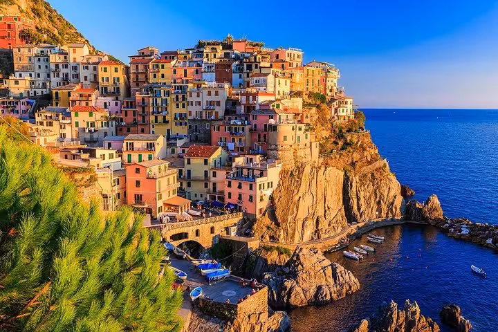 Manarola village at sunset in Cinque Terre, Italy, showcasing vibrant houses perched on a rugged coastline.