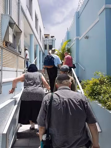 Visitors walking up steps to a Manaus synagogue entrance on a guided Jewish heritage tour in the Amazon