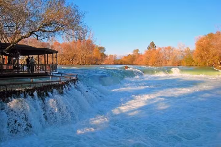 Wide view of Manavgat Waterfall in Antalya on a private Side tour, foaming rapids, trees and riverside deck