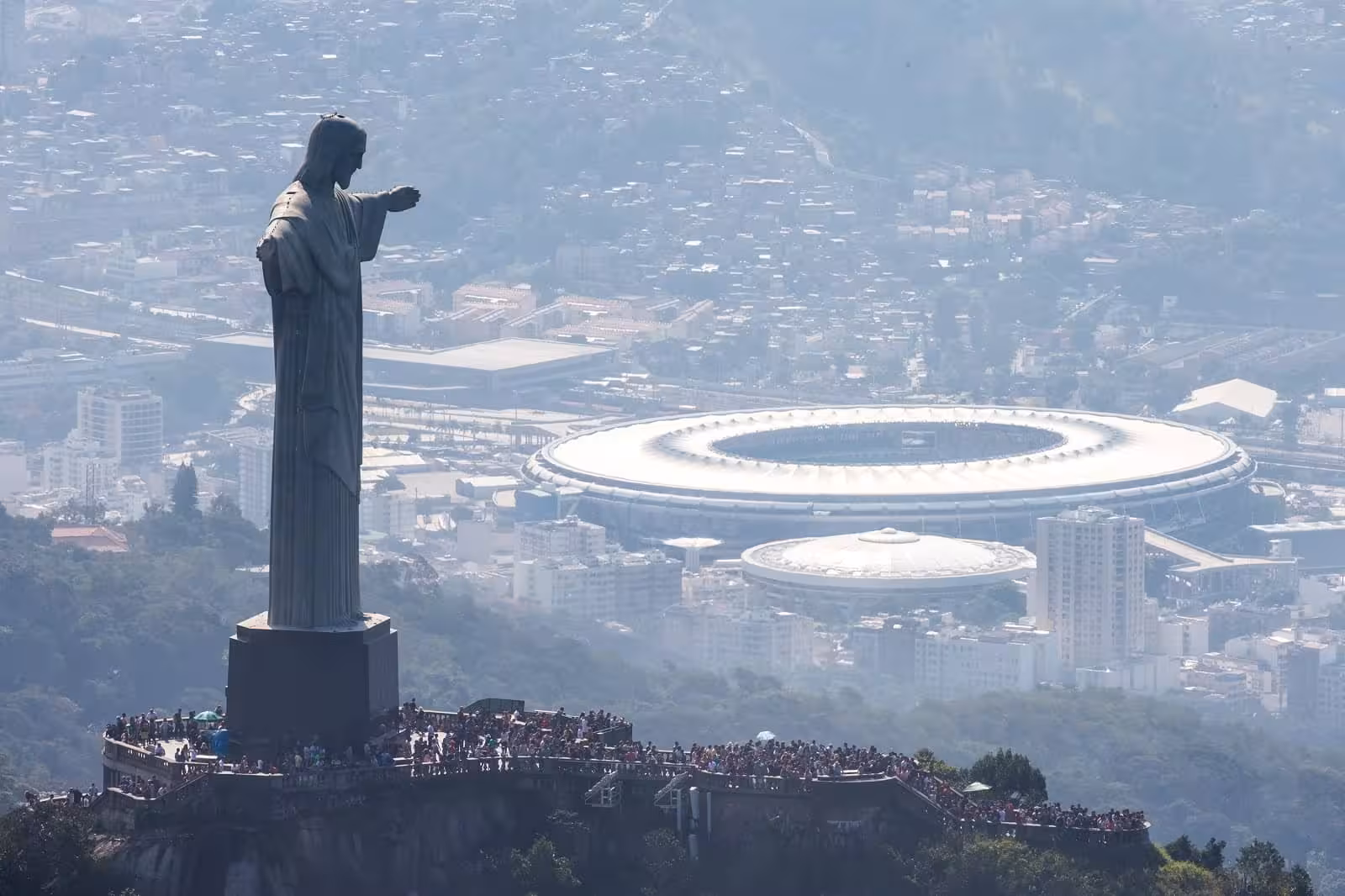 Aerial view of Rio's iconic Maracanã Stadium with Christ the Redeemer statue overlooking the city, ideal for a football tour.