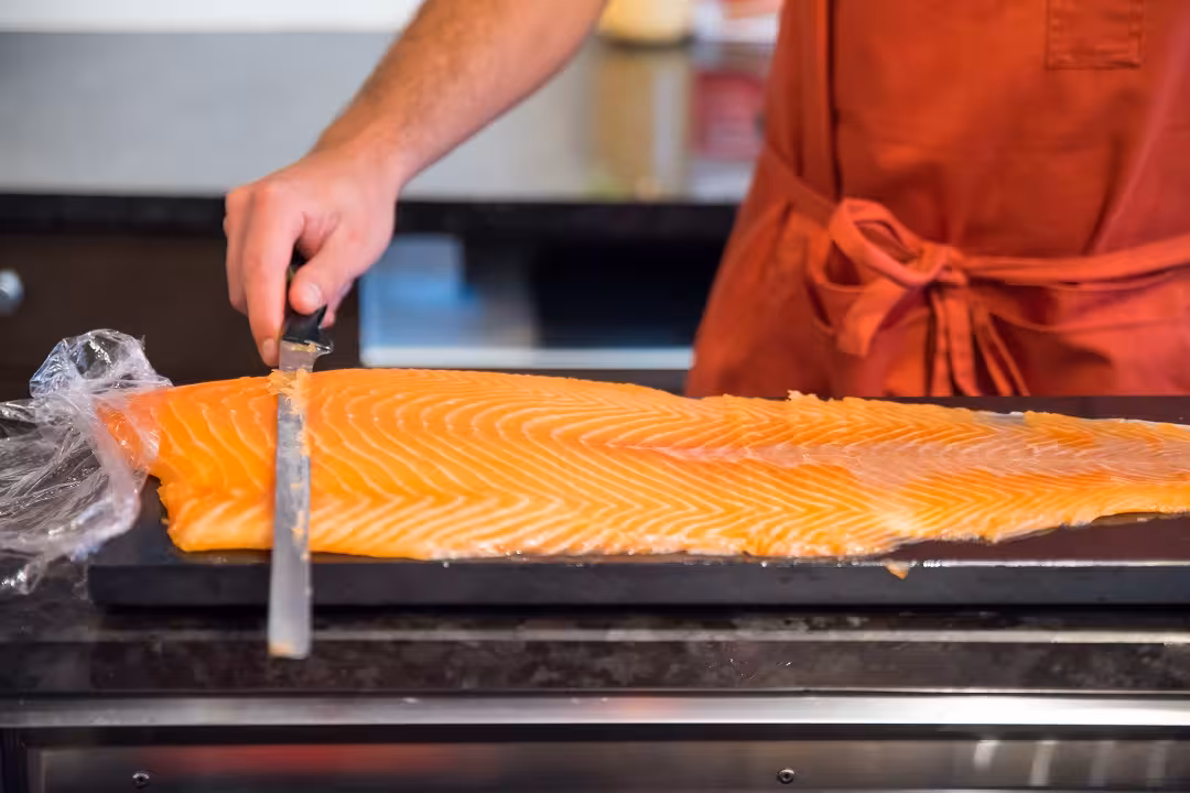 Person expertly slicing fresh salmon during the Marais District food tour with wine and cheese tastings.