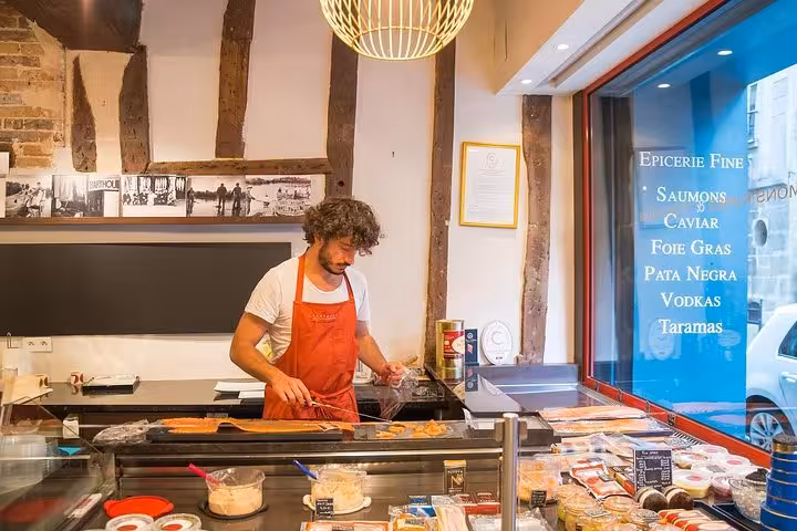 A chef prepares gourmet food in a Parisian deli, showcasing fine French ingredients on The Marais Food Tour.