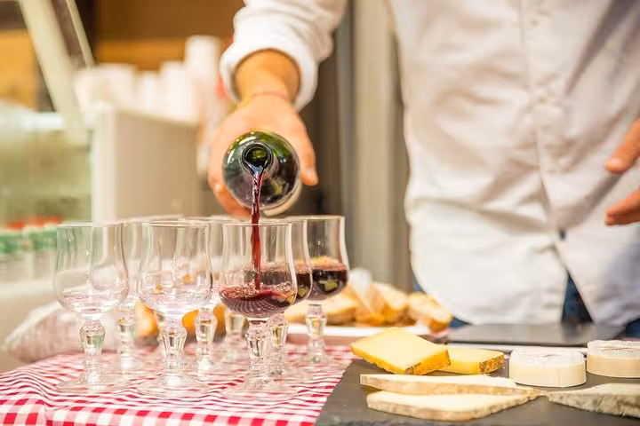 Wine being poured into glasses with a selection of cheeses on the Marais food tour in Paris.