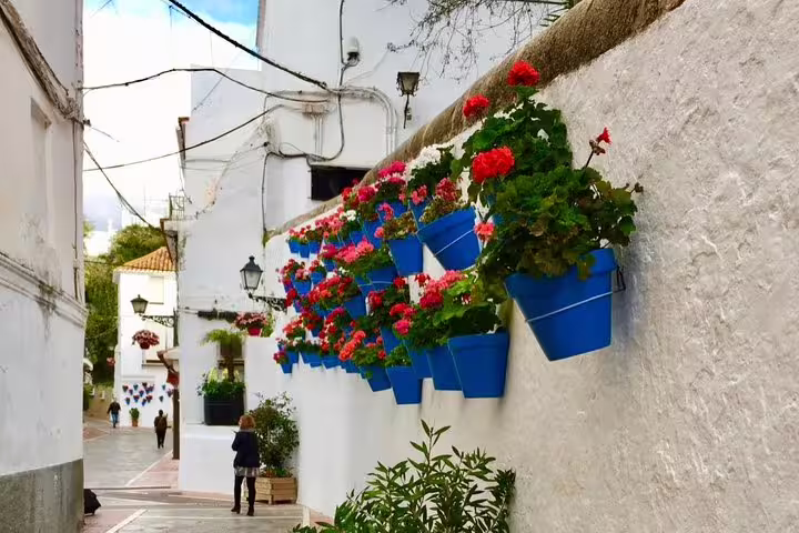 Picturesque alley in Marbella Old Town featuring colorful flower pots on white walls, creating a vibrant atmosphere.