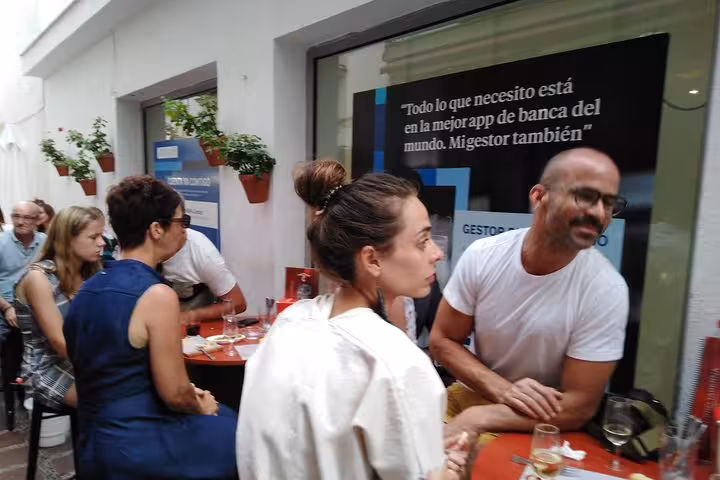 Visitors enjoying lively conversations and tapas on a bustling street in Marbella, Spain.