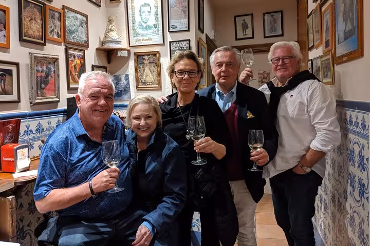 Visitors enjoying wine and camaraderie in a charming Marbella tapas bar, surrounded by local art and decor.