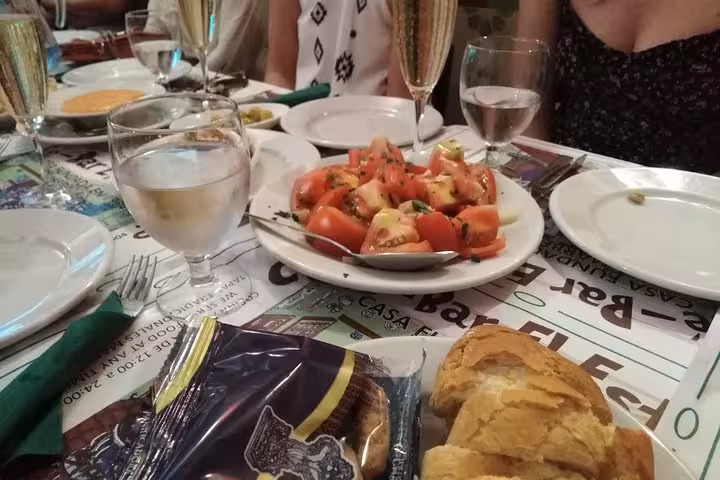 Vibrant Marbella tapas spread with fresh tomato salad, crusty bread, and sparkling drinks on an inviting table setting.
