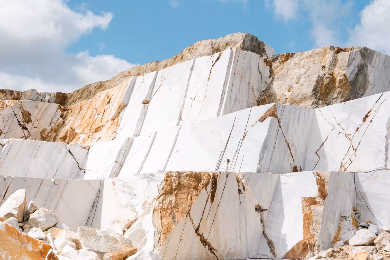 Wide view of stepped white marble quarry cliffs and rock piles, showcasing the Marble World marble landscape tour