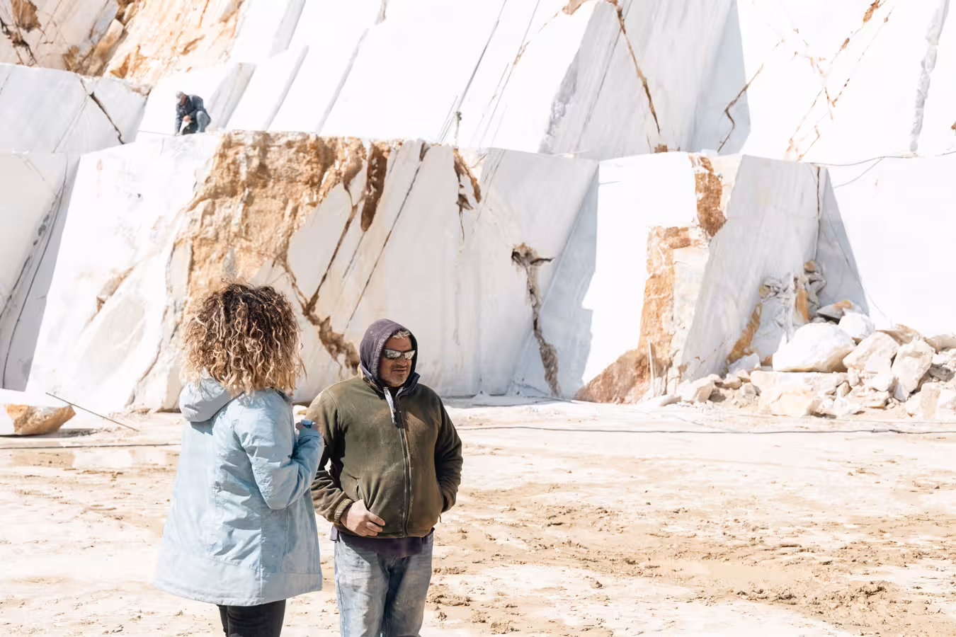 Visitors meet a local guide at a white marble quarry on the Marble World tour, surrounded by giant slabs