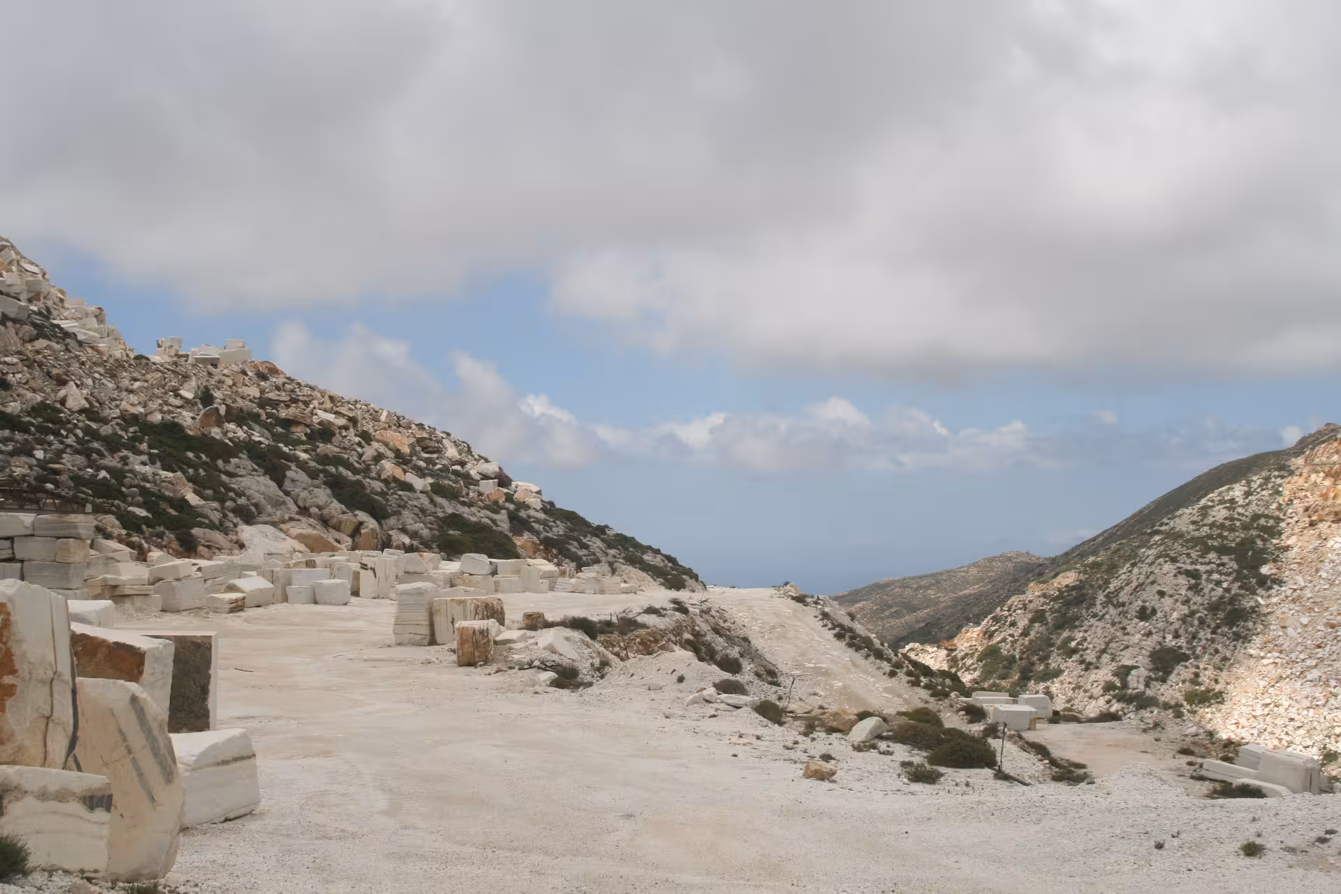 Scenic marble quarry road in Marble World with white stone blocks and mountain views under cloudy sky