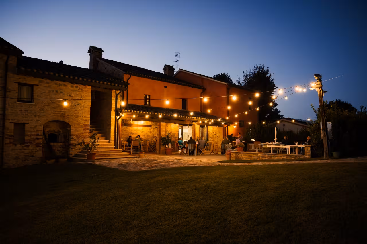 Evening farmhouse dining in Marche after a handmade pasta class, with string lights and outdoor tasting tables