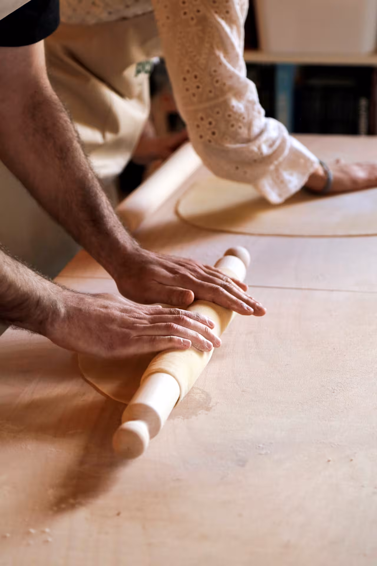Hands rolling fresh pasta dough with a wooden pin during a Marche handmade pasta cooking class experience