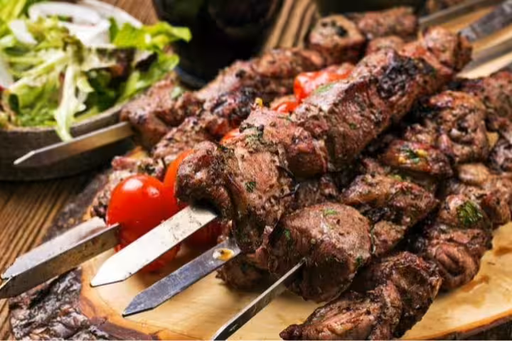 Close-up of marinated beef espetada skewers served with fresh salad, highlighting Madeira's authentic culinary delights.