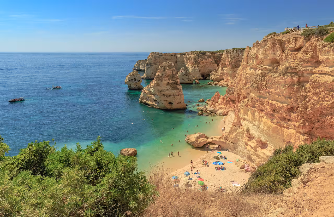 Secluded Marinha Beach on the Algarve coast with golden cliffs, turquoise water and boats on a Benagil Caves private tour