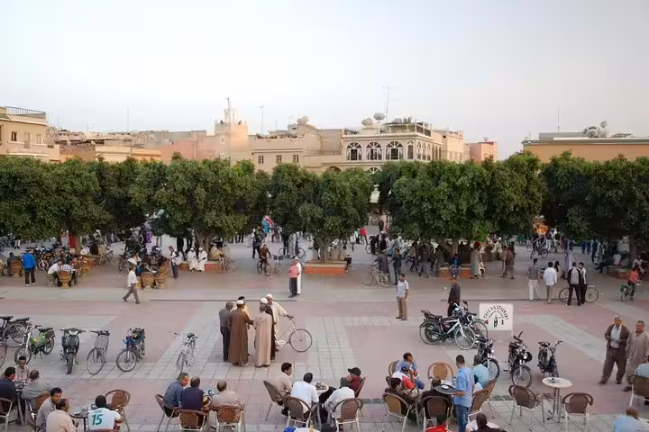 Bustling Marrakech square with cyclists and cafes, starting point for Morocco Anti-Atlas & Sahara 8-day tour