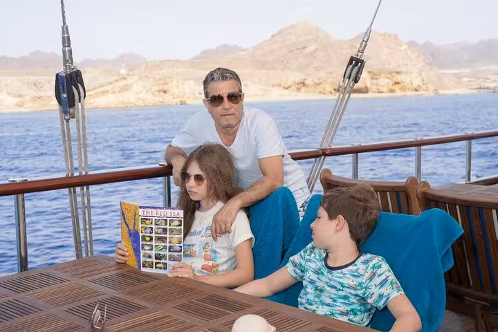Family lounging on Marsa Alam pirates sailboat cruise with pickup, enjoying Red Sea coastline near Turtle Bay