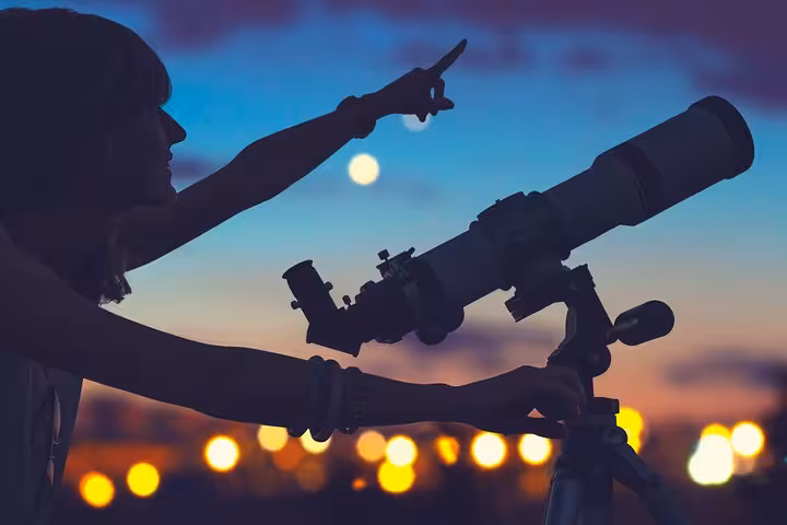 Traveler using telescope on Marsa Alam stargazing jeep safari with Bedouin camp dinner in the desert night