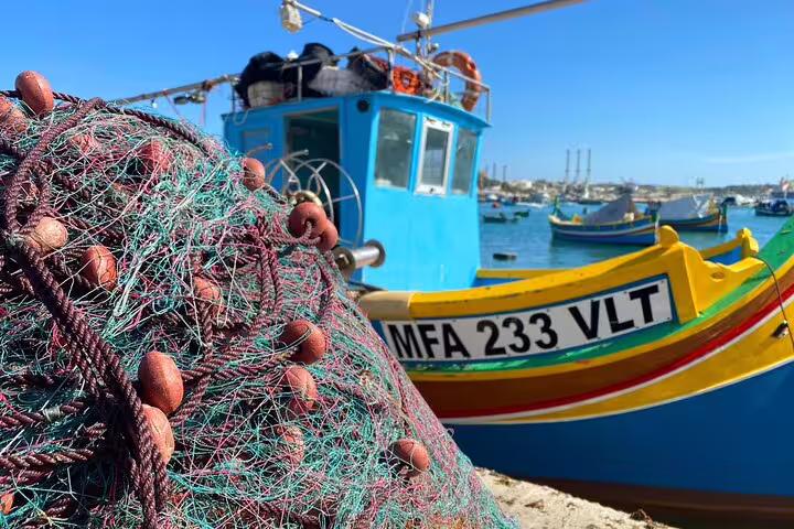 Colorful fishing boat and nets at Marsaxlokk Sunday Market, showcasing authentic Maltese maritime culture.