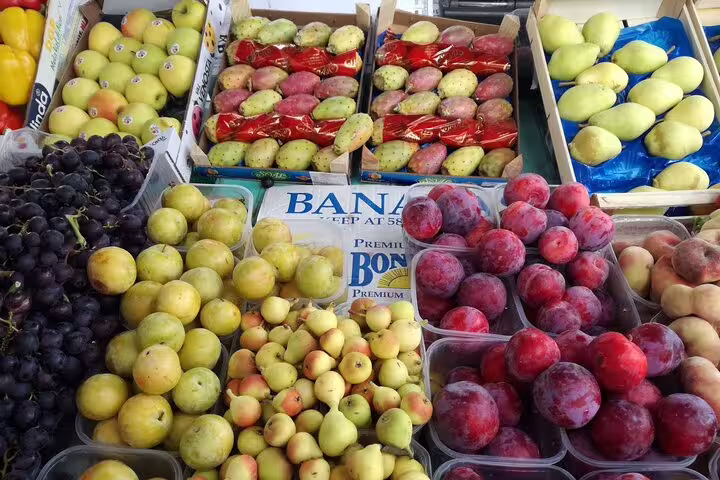 A variety of fresh fruits, including grapes, plums, and prickly pears, displayed at Marsaxlokk Sunday Market.