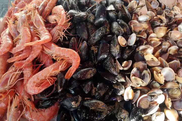 Fresh seafood display at Marsaxlokk Sunday Market featuring vibrant prawns, mussels, and clams, highlighting local culinary delights.