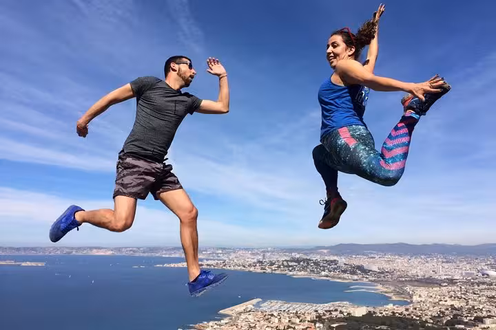 Hikers jumping on Marseille viewpoint above Les Calanques, panoramic coastal hike with Mediterranean views