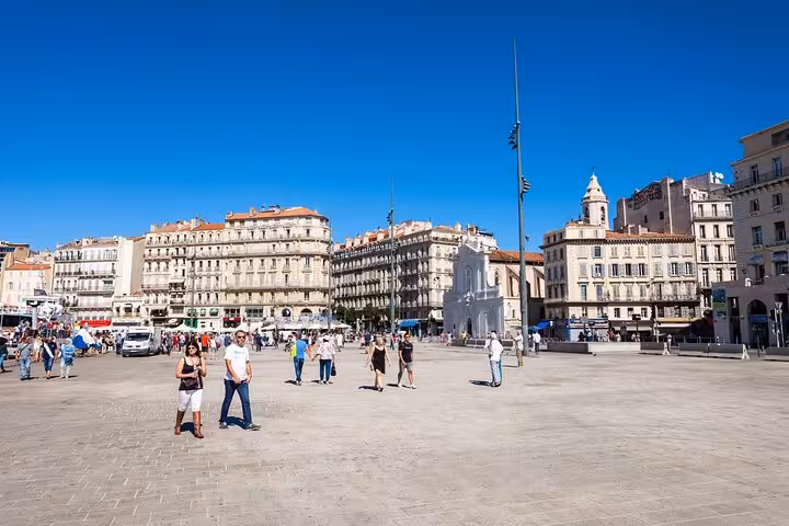 Visitors strolling through a bustling square surrounded by historic buildings in Marseille city center.
