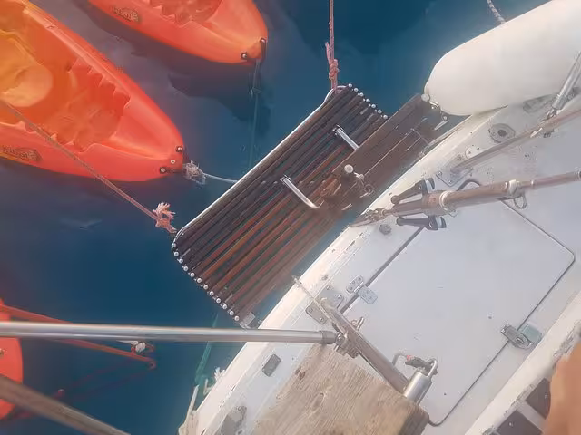 Swim ladder and orange kayaks beside a sailboat in Marseille, perfect for sea bathing on a windy sailing excursion