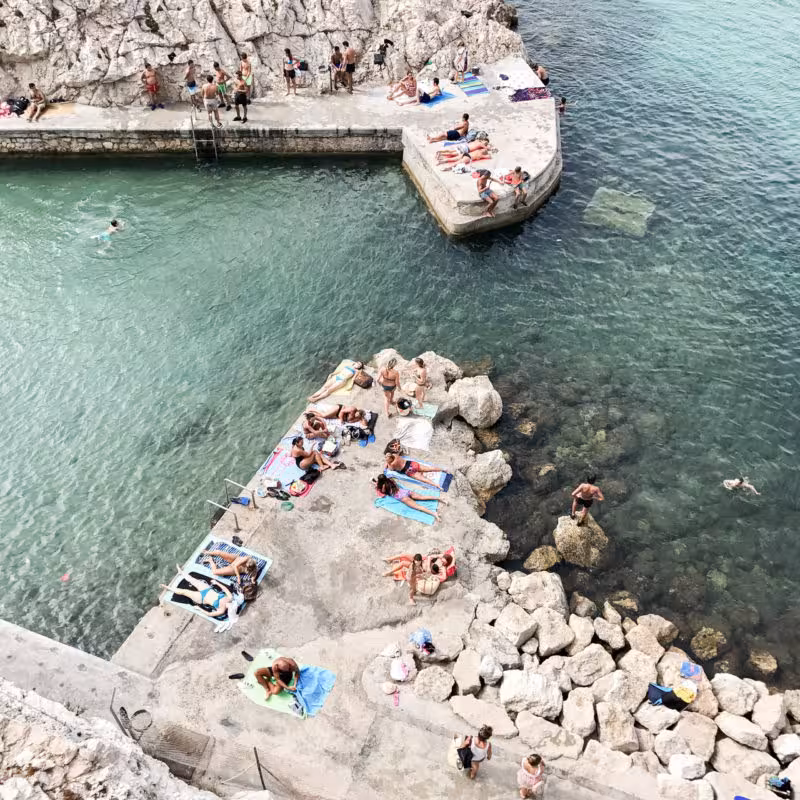 Swimmers and sunbathers at a rocky sea pool in Marseille on the urban hike from St. Victor to the coast